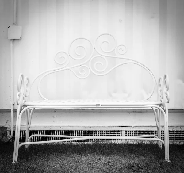 Белая скамейка на белой бетонной стене — стоковое фото