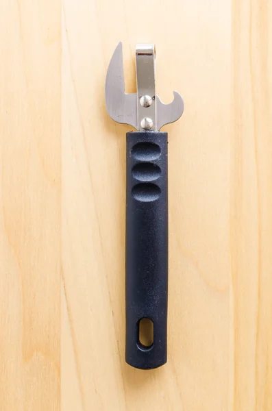 Can opener on wood background — Stock Photo, Image