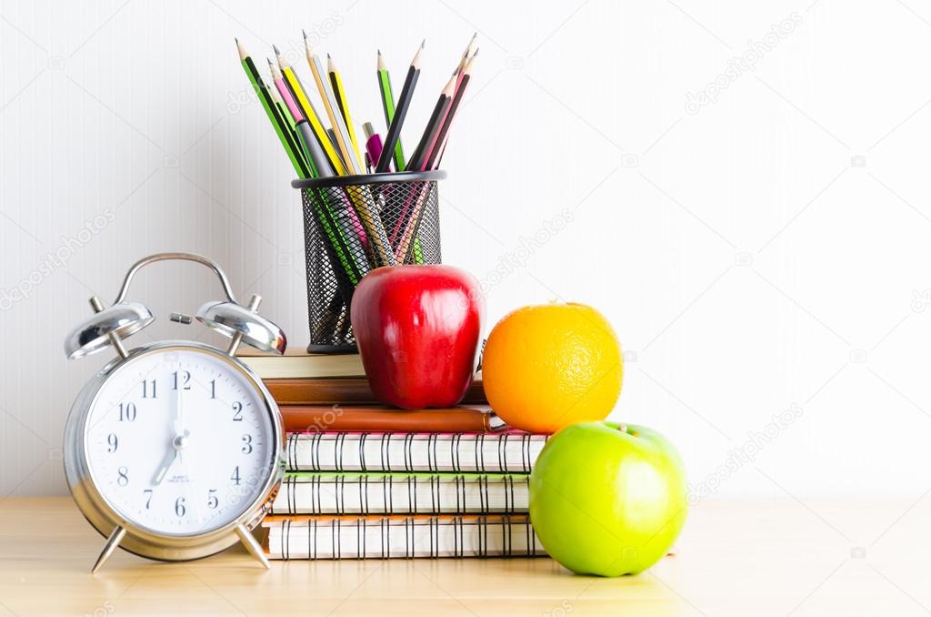 Note book , clock , pencils , apples