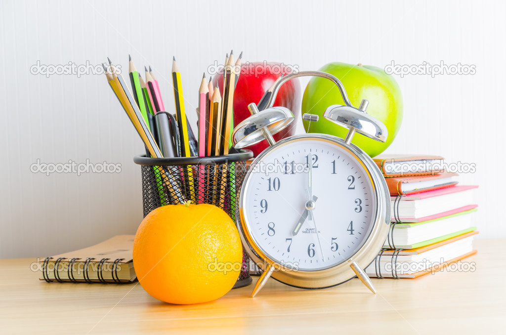 Note book, clock, pencils, apples