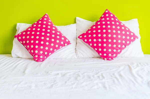 Almohada de polka colorida en la cama blanca — Foto de Stock