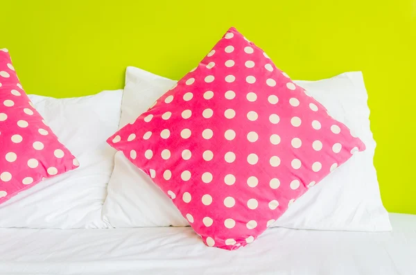 Barevné polka polštář na bílé posteli — Stockfoto