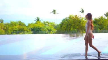 Güzel bir Asyalı kadın portresi tatil köyünde yüzme havuzunda rahatlıyor.