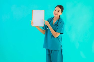 Fotokopi için boş kâğıt tahtası olan güzel Asyalı genç doktor kadın hastane ve klinikteki sağlık hizmetleri konseptinde mavi izole edilmiş arka plan.