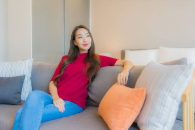 Güzel bir Asyalı kadın portresi. Yatak odasındaki kanepede rahatla. Gülümse.