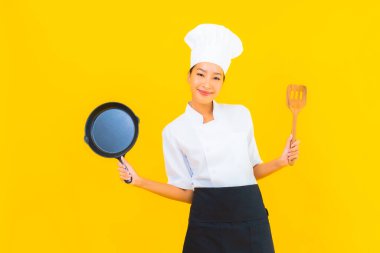 Sarı izole arka planda siyah şapkalı güzel Asyalı şef kadın portresi.
