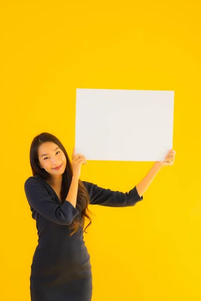 Portrait beautiful young asian woman with empty and blank billboard card banner on yellow isolated background