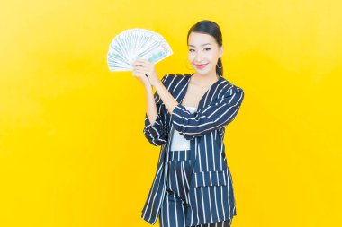 Asyalı güzel bir kadının portresi. Renkli arka planda bol para ve parayla gülümsüyor.