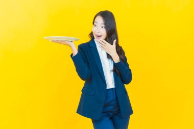 Güzel Asyalı bir kadının portresi. Arka planda boş tabak tabağıyla gülümsüyor.