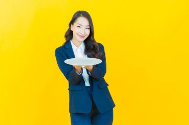 Güzel Asyalı bir kadının portresi. Arka planda boş tabak tabağıyla gülümsüyor.