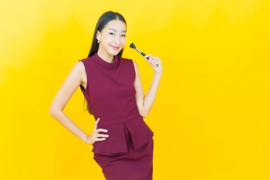 Renk arka planında makyaj fırçası olan güzel Asyalı kadın portresi.