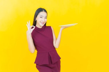 Güzel Asyalı bir kadının portresi. Arka planda boş tabak tabağıyla gülümsüyor.