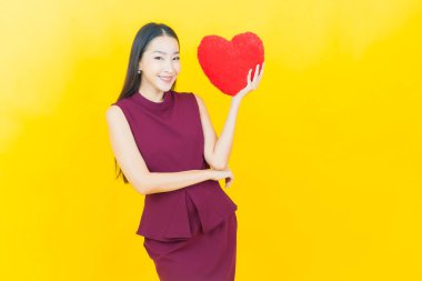 Güzel bir Asyalı kadının portresi. Arka planda kırmızı hediye kutusuyla gülümsüyor.