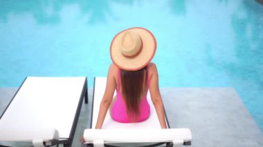 Güzel bir Asyalı kadın portresi tatil köyünde yüzme havuzunda rahatlıyor.