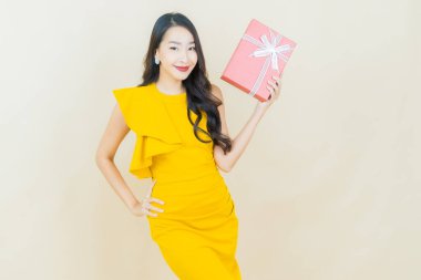 Güzel bir Asyalı kadının portresi. Arka planda kırmızı hediye kutusuyla gülümsüyor.