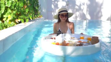 Güzel bir Asyalı kadın portresi tatil köyünde yüzme havuzunda rahatlıyor.