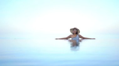 Güzel bir Asyalı kadın portresi tatil köyünde yüzme havuzunda rahatlıyor.