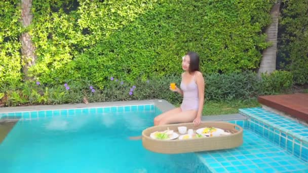 美しい若いアジアの女性がリゾートの屋外スイミングプールでリラックス — ストック動画
