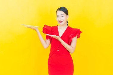 Güzel Asyalı bir kadının portresi. Arka planda boş tabak tabağıyla gülümsüyor.