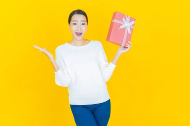 Güzel bir Asyalı kadının portresi. Arka planda kırmızı hediye kutusuyla gülümsüyor.