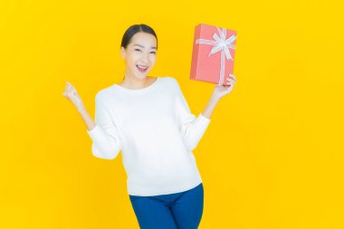 Güzel bir Asyalı kadının portresi. Arka planda kırmızı hediye kutusuyla gülümsüyor.