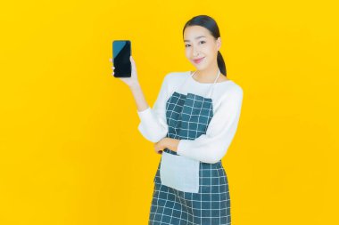 Renkli arka planda akıllı cep telefonuyla güzel Asyalı kadın gülümsemesi