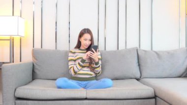Güzel Asyalı kadının evde akıllı telefon kullandığının görüntüleri.