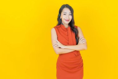 Sarı arka planda çağrı merkezi müşteri hizmetleri merkezi olan güzel Asyalı kadın portresi