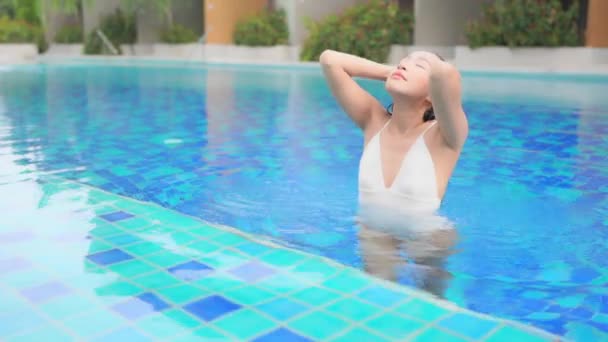 亚洲年轻貌美的女子在度假胜地的室外游泳池里放松一下 — 图库视频影像