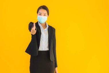 Güzel genç iş kadını portresi Korunmak için maske takıyor 19 koronavirüs sarı izole arka planda