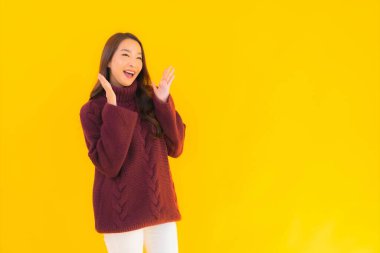 Güzel Asyalı kadın gülümsüyor. Sarı izole edilmiş arka planda başka bir eylemde mutlu.