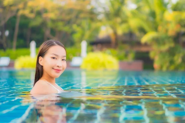 美しい若いアジアの女性は休日の休暇のために海のビーチの海の近くの屋外スイミングプールの周りの笑顔のレジャーをリラックス — ストック写真