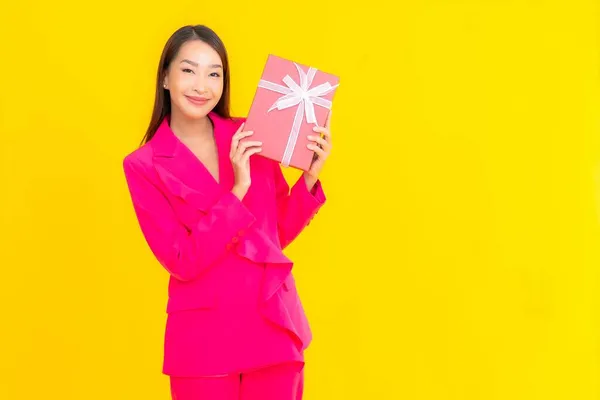 亚洲年轻貌美的女性形象与红色礼品盒的黄色隔离背景 — 图库照片