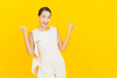 Asyalı güzel bir kadının portresi. Sarı arka planda hareketli gülümsüyor.