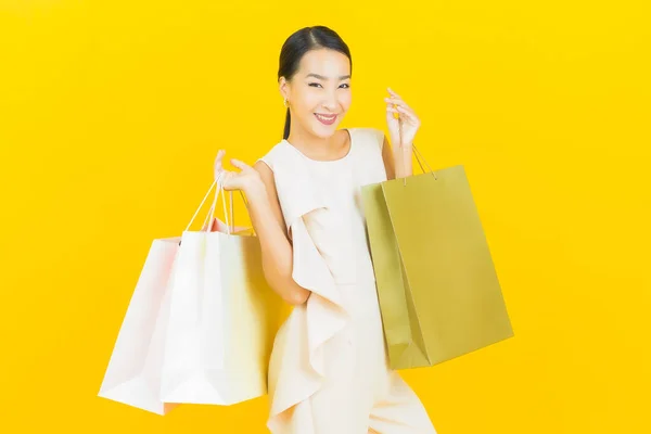 肖像画美しい若いアジアの女性の笑顔でショッピングバッグで黄色の色の背景 — ストック写真