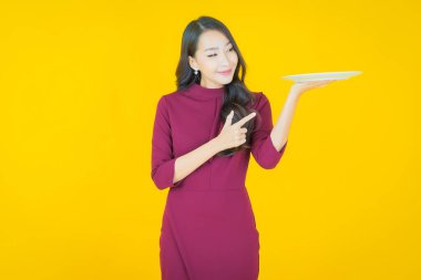 Güzel Asyalı bir kadının portresi. Arka planda boş tabak tabağıyla gülümsüyor.