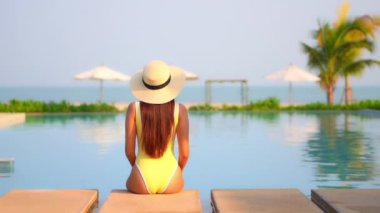 Güzel bir Asyalı kadın portresi tatil köyünde yüzme havuzunda rahatlıyor.