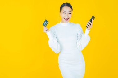 Güzel bir Asyalı kadının portresi. Renkli kredi kartıyla gülüyor.