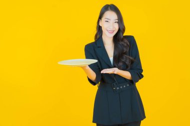 Güzel Asyalı bir kadının portresi. Arka planda boş tabak tabağıyla gülümsüyor.