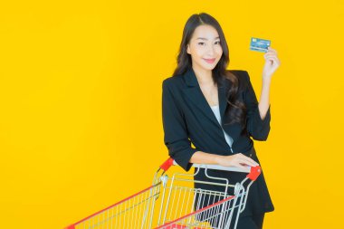 Renkli arka planda süpermarketten alınmış market sepetiyle gülümseyen güzel Asyalı kadın portresi.