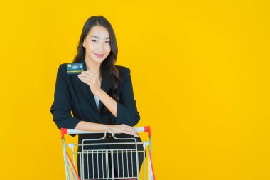 Renkli arka planda süpermarketten alınmış market sepetiyle gülümseyen güzel Asyalı kadın portresi.