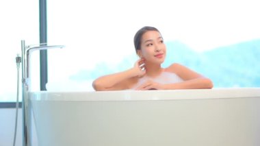 Güzel Asyalı bir kadının pencerenin önünde banyo yaptığı görüntüler.