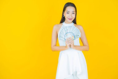 Asyalı güzel bir kadının portresi. Renkli arka planda bol para ve parayla gülümsüyor.