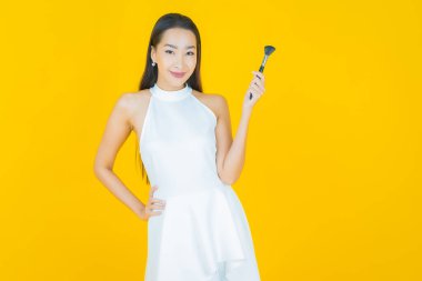 Renk arka planında makyaj fırçası olan güzel Asyalı kadın portresi.