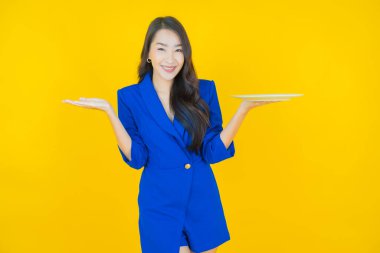 Güzel Asyalı bir kadının portresi. Arka planda boş tabak tabağıyla gülümsüyor.