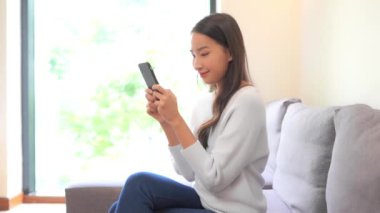 Güzel Asyalı kadının evde akıllı telefon kullandığının görüntüleri.