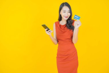 Renkli arka planda akıllı cep telefonuyla güzel Asyalı kadın gülümsemesi