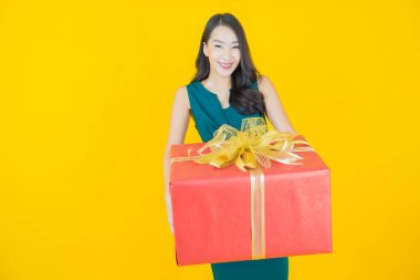 Güzel bir Asyalı kadının portresi. Arka planda kırmızı hediye kutusuyla gülümsüyor.