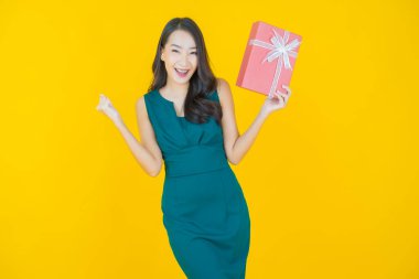 Güzel bir Asyalı kadının portresi. Arka planda kırmızı hediye kutusuyla gülümsüyor.