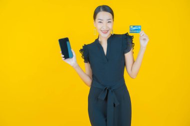 Güzel bir Asyalı kadının portresi. Renkli kredi kartıyla gülüyor.